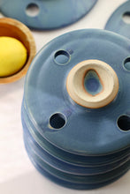 Load image into Gallery viewer, overhead photo of 4 bright blue colored 5 inch circular disc shaped ceramic cooking stones with an exposed ceramic handle.